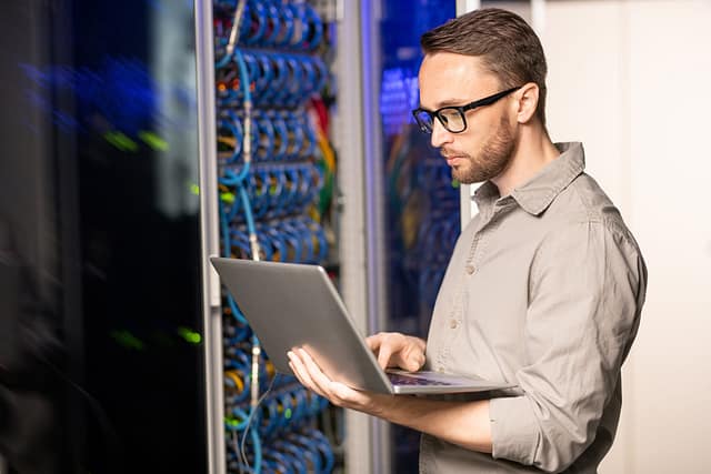 Network engineer working in a server room with a laptop