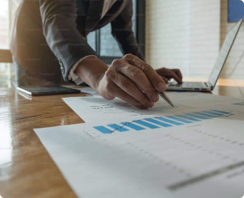 Business professional analyzing data reports with charts and graphs on paper at a desk